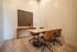 Modern meeting space with sleek wooden table, stylish chairs, and elegant art piece on the wall.