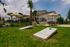 Inviting outdoor recreational area with cornhole game, shaded seating, and lush greenery, perfect for relaxation and socializing.