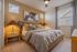 Cozy bedroom with elegant decor, featuring a plush bed, stylish lamps, and modern artwork, bathed in natural light through ample windows.
