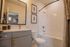 Elegant bathroom with a large mirror, modern vanity, and a pristine bathtub surrounded by stylish decor.