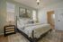 Inviting bedroom with stylish decor, featuring a cozy upholstered bed, two elegant windows, and ambient lighting for a serene retreat.