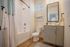 Modern bathroom with elegant fixtures, featuring a pristine white bathtub, stylish vanity, and natural light enhancing a serene ambiance.
