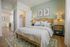 Charming bedroom featuring a cozy bed with elegant pillows, stylish woven headboard, and refined gold-accented lamps, creating a serene retreat.