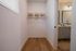 Chic walk-in closet with wooden flooring, stylish basket storage, and open hangers leading to a modern bathroom vanity.