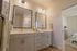 Elegant bathroom with double vanity, stylish lighting, and seamless transition to a cozy bedroom.