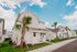 Charming suburban home with modern exterior, surrounded by lush greenery and palm trees, under a bright blue sky.