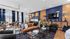 Contemporary living space with chic decor, featuring a cozy brown leather sofa, elegant blue accents, and modern lighting fixtures, perfect for relaxation and entertainment.