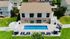 Inviting community pool area with sun loungers, umbrellas, and lush greenery surrounding a modern building.