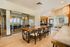 Modern communal area featuring a long wooden dining table, stylish chairs, and glass walls, creating an open and inviting space.