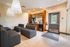 Chic and modern lounge area featuring sleek gray seating with contemporary lighting, a stylish mini bar, and bright accents perfect for relaxation.
