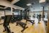 Modern fitness center with state-of-the-art equipment, including free weights, benches, and exercise machines, on a sleek wooden floor.