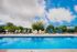 Inviting swimming pool with plush lounge chairs and vibrant umbrellas, set against a picturesque sky and lush greenery.