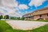 Charming suburban homes with a sunlit backyard featuring a private sand volleyball court and lush trees, perfect for outdoor activities.