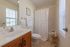 Bright and airy bathroom with elegant wooden cabinetry, a full bathtub with patterned curtain, and charming decorative accents.