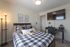 Inviting bedroom with stylish decor, featuring a cozy bed, elegant lighting, and a modern workspace equipped with a large TV.