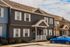 Charming row of suburban townhouses with colorful facades, featuring welcoming front porches and a neatly parked blue car in the driveway.