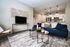 Contemporary living area with a navy blue sofa, elegant coffee tables, stylish kitchen, and chic pendant lighting.