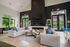 Inviting living room with high ceilings, elegant fireplace, and natural light from large windows, complemented by comfortable seating and a modern decor.