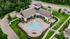 Aerial view of a luxurious community center featuring a chic swimming pool surrounded by elegant lounge chairs and lush green landscaping.