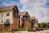 Charming multi-story apartment building with modern balconies, surrounded by lush greenery and ample parking.