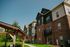 Charming brick apartment complex surrounded by lush greenery and a cozy outdoor seating area.