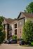 Charming modern apartment building with inviting balconies, set amidst lush greenery and ample parking space.