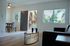 Bright and inviting living space with modern decor, featuring large windows, an open entryway, and a cozy dining area.