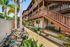 Charming apartment exterior with wooden balconies, lush tropical landscaping, and convenient bike parking.
