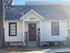 Charming white cottage with a dark roof and welcoming front porch, featuring the number 1027 above the door.