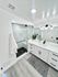 Elegant bathroom featuring a glass-enclosed shower, white vanity with black fixtures, and hardwood floors.