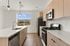 Modern kitchen with sleek wooden cabinets, stainless steel appliances, and a stunning mountain view through a large window.