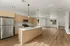 Bright and modern open-concept kitchen and living space with sleek stainless steel appliances and elegant wood flooring.