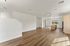 Bright and spacious open-concept living area with elegant hardwood floors, modern recessed lighting, and a sleek kitchen island under natural light.