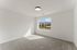 Bright unfurnished room with large window offering stunning mountain views and soft carpeting.