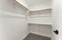 Spacious walk-in closet with pristine white walls and sleek shelving, perfect for ample storage and organization.