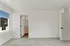 Bright, spacious room with modern beige carpeting, a sleek bathroom entry, and a large window offering a scenic view.