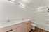 Elegant bathroom with modern dual sinks, stylish wood cabinetry, and bright lighting, offering a perfect blend of functionality and design.
