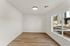 Bright and spacious unfurnished room with large window and sleek hardwood flooring, offering potential for customization and natural light.