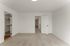 Bright and spacious empty room with plush carpet, featuring a walk-in closet and a modern white door leading to a hallway.