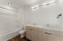 Sleek and modern bathroom featuring a double sink vanity, stylish wood cabinetry, and a pristine bathtub with elegant lighting.