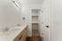 Modern bathroom with dual sinks, stylish wood cabinetry, and a spacious closet alcove.