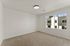 Bright and spacious room with soft carpet flooring and a large window offering views of modern architecture.