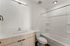 Modern bathroom featuring sleek white countertop, elegant wooden cabinetry, and a spacious bathtub.