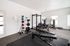 Modern fitness room equipped with state-of-the-art cardio machines, weight racks, and swiss balls, perfect for an active lifestyle.