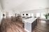 Spacious modern room with elegant wooden flooring, abundant natural light, stylish seating, and a sleek kitchen island.