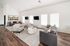 Bright and airy living room featuring modern gray sofas, sleek TV setup, and elegant wood flooring for a contemporary ambiance.