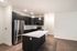 Modern kitchen with sleek dark cabinets, stainless steel appliances, and a spacious quartz island, perfect for entertaining.