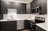 Modern kitchen with sleek dark cabinets, stainless steel appliances, and elegant white countertops, creating a stylish and functional space.