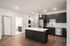 Modern kitchen in open-plan apartment featuring sleek dark cabinets, a spacious island, and stainless steel appliances. Contemporary design with elegant pendant lighting and pristine wooden flooring.