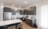 Modern kitchen with sleek gray cabinets, stainless steel appliances, and a bright, spacious layout accentuated by elegant lighting fixtures.